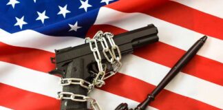 A handgun chained on an American flag with a gavel beside it