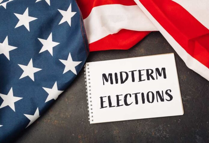 A,White,Piece,Of,Paper,With,The,Words,Midterm,Elections American flag and a notebook with 'MIDTERM ELECTIONS' written on it