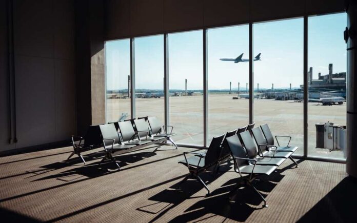 Empty,Airport,Terminal,Seating,Area,With,A,Large,Window,View View of an airport waiting area with an airplane taking off in the background