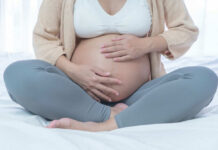 Pregnant woman sitting crosslegged on bed
