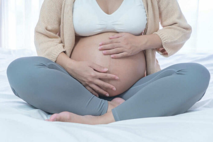 shutterstock_2474304531 Pregnant woman sitting crosslegged on bed