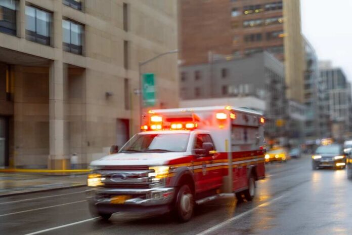 A,Blurred,Ambulance,Races,Through,The,Bustling,Streets,Of,New Ambulance with flashing lights driving on a wet city street