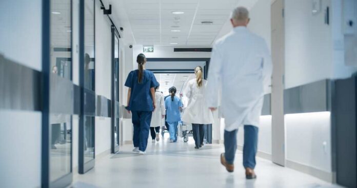 Hospital,Hallway,With,Doctors,,Nurses,And,Specialists,In,Hospital.,Female Medical staff walking through a hospital corridor