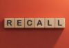 Wooden letter tiles spelling recall on an orange background