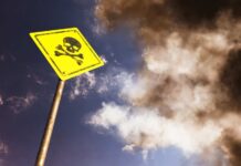 Grim Find – At Least 14 Dead Yellow skull and crossbones warning sign against smoky sky