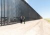 Record Border Deal, Sudden Freeze Group of people walking by a border fence.