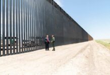 Record Border Deal, Sudden Freeze Group of people walking by a border fence.
