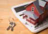 Rich Buyers Feast, Starters Get Squeezed A miniature red house on a calculator with keys nearby