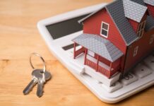 Rich Buyers Feast, Starters Get Squeezed A miniature red house on a calculator with keys nearby