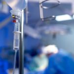 NEWS ALERT: Deadly Mix-Up Inside OR IV drip in focus with surgeons operating in the background