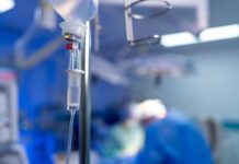 NEWS ALERT: Deadly Mix-Up Inside OR IV drip in focus with surgeons operating in the background