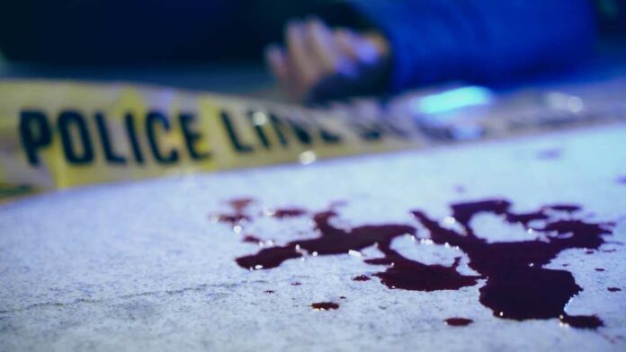 Dead,Body,Near,Blood,Stains,And,Police,Line,Tape,On Blood on pavement with police tape and a hand in the background