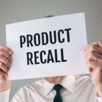 Person holding a sign reading product recall