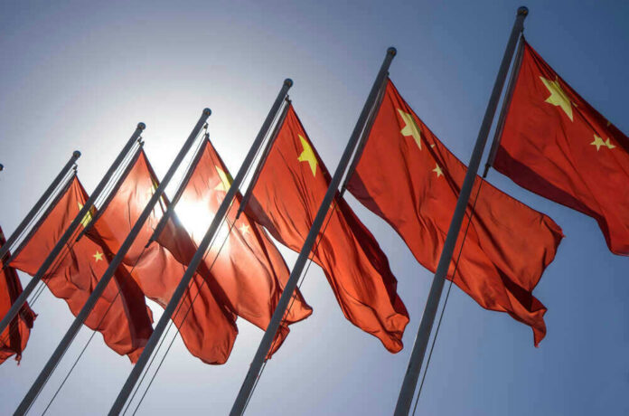 shutterstock_325058183 Chinese flags waving under a clear sky.
