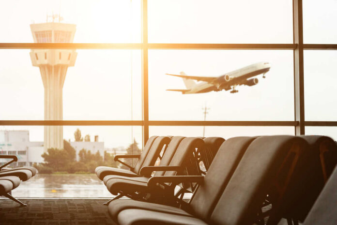 Empty,Chairs,In,The,Departure,Hall,At,Airport,,,With View of an airport terminal with an airplane taking off in the background