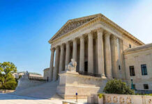 Supreme Court Justice Backs Out In Stunning Move Stone building with columns and statues, clear blue sky.
