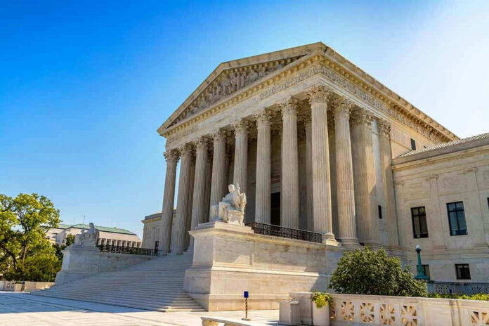 2365573473 Stone building with columns and statues, clear blue sky.