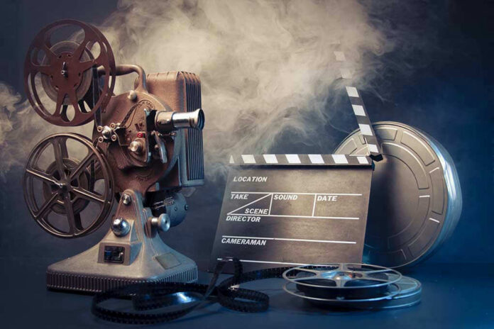 Vintage film projector and clapperboard with reels.