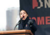 AOC’s Announcement Rattles Democrats Alexandria Ocasio-Cortez passionately speaking at a podium outside.
