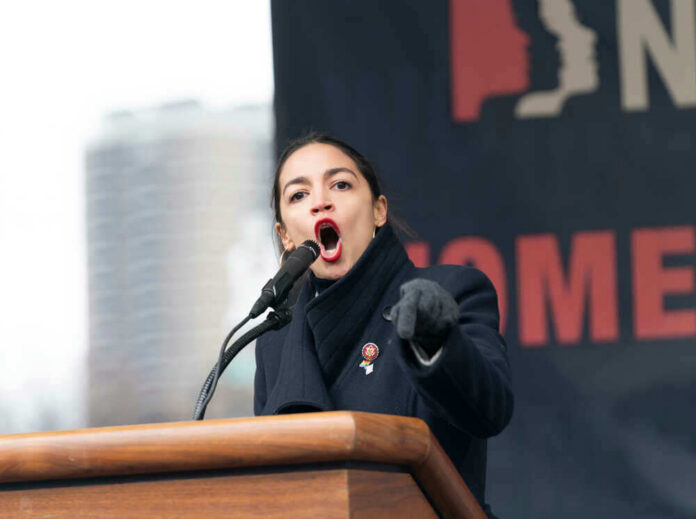 shutterstock_1289128282 Alexandria Ocasio-Cortez passionately speaking at a podium outside.