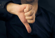 This U.S. Dry-Up Stuns Researchers Hand showing thumbs down gesture, dark background.