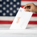 Supreme Court Shocker: Late Ballots Live Hand inserting mail-in ballot envelope into ballot box