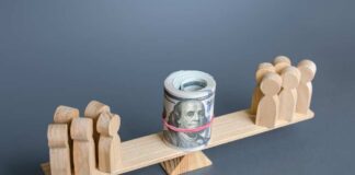 Wooden figures balancing a roll of money on a seesaw