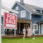 Wall Street Landlords Hit With Shock Freeze For sale sign in front of a house with potential buyers discussing