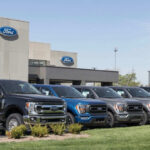 Hands-Free Hauling? Famed Pickup Pushes 10,000 Pounds Ford dealership with trucks lined up outside