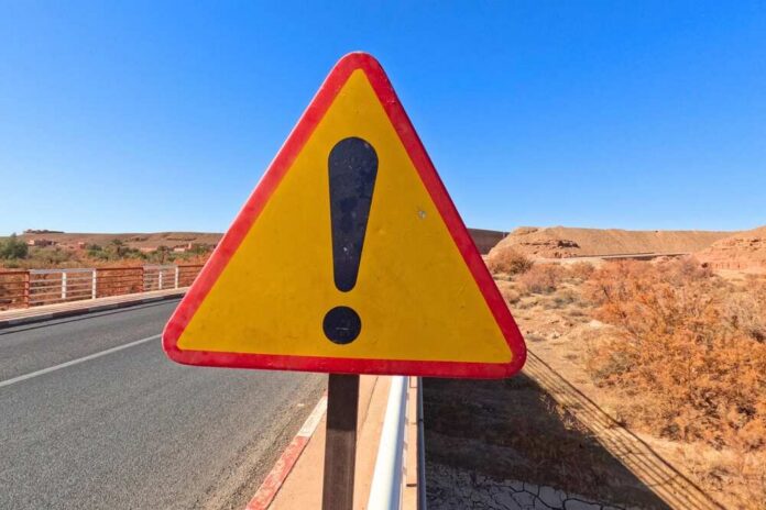 Triangular warning road sign with exclamation mark on a rural highway