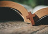 Open Bible with a wooden cross on it.
