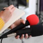 Historic Baby Born In Washington Journalist holding two microphones while writing in a notebook