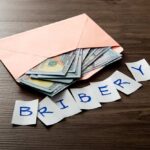 Money Blitz Flattens Cori Bush Envelope with cash and notes spelling bribery on wooden table