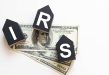 NOW: Surprise IRS Letters Promise Big Payouts Blocks spelling 'IRS' placed on top of hundred dollar bills featuring Benjamin Franklin