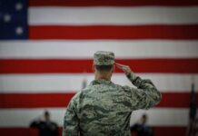 VIDEO: U.S. Strikes Back – New Military Action A military personnel saluting in front of a large American flag