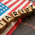 Airfare Truth Fight Reignites Wooden blocks spelling 'TARIFFS' on a background of the US flag and financial charts