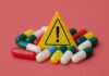 Mouse Pill Torches Fat, Spares Muscle? Warning sign among assorted capsules on pink background