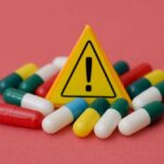 Mouse Pill Torches Fat, Spares Muscle? Warning sign among assorted capsules on pink background