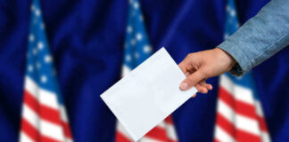 Hand casting a vote into a ballot box.