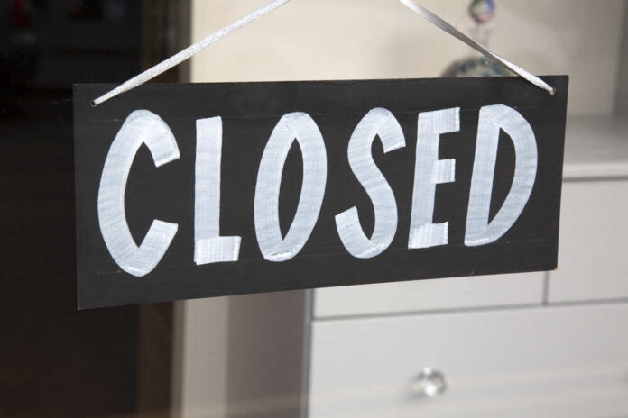 Closed,Sign,On,Shop,Window A black sign with the word 'CLOSED' painted in white letters