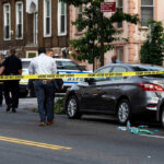 Parking Rage Kills Child At Football Park Police and crime scene tape on city street.