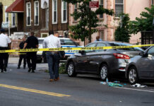 Parking Rage Kills Child At Football Park Police and crime scene tape on city street.