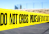 Police do not cross tape stretched across an outdoor scene
