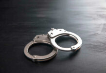 Governor Offers Reprieve, No Freedom Metal handcuffs on a dark textured surface.