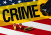 A gun and bullets on an American flag with a crime scene marker