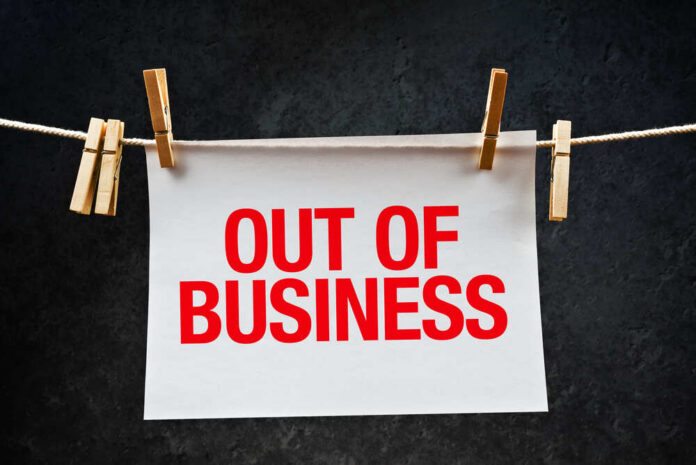 Out,Of,Business,Note,Printed,On,Paper,Hanging,On,Rope paper sign with red lettering clipped to a clothesline