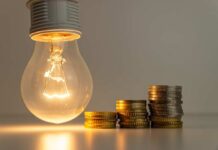 SHOCKING: Skip Meals Or Keep Lights On? A glowing light bulb next to stacks of coins