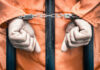 DNA Bombshell Upends THIS Death Row Case Handcuffed person in orange jumpsuit behind prison bars.
