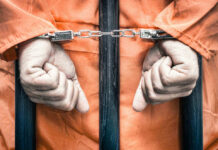 DNA Bombshell Upends THIS Death Row Case Handcuffed person in orange jumpsuit behind prison bars.