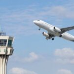 An airplane taking off near an airport control tower